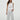 Woman wearing a white sleeveless top and pants on a plain background