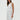 Woman wearing a white sleeveless top and pants on a plain background
