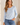 A woman wearing a light blue  long sleeve crew tee and blue jeans on a white background.
