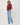 A woman modeling a sleeveless maroon top and light blue wide-leg jeans against a plain light gray studio background.