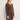 A woman wearing a knit v neck brown sweater and brown knit pants on a white background