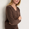 A woman wearing a knit v neck brown sweater and brown knit pants on a white background