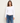 A woman wearing a white cropped long sleeve and blue jeans on a white background 