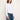 A woman wearing a white cropped long sleeve and blue jeans on a white background 