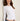 A woman wearing a white cropped long sleeve and blue jeans on a white background 
