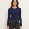 A woman wearing a navy cropped long sleeve and black jeans on a white background 
