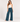 A woman wearing teal ribbed foldover pants, a white tank and sneakers on a white background.