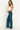 A woman wearing teal ribbed foldover pants, a white tank and sneakers on a white background.
