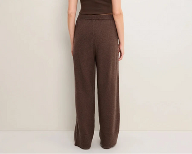 A woman wearing brown knit pants on a white  background