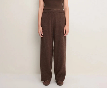 A woman wearing brown knit pants on a white  background