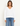 A woman facing foreward wearing a white v-neck long sleeve and blue jeans on a white background.