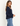 A woman facing sideways wearing a navy v-neck long sleeve and blue jeans on a white background.