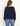 a woman facing backwards wearing a navy long sleeve top and blue jeans on a white background.