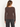 a woman facing backward in a ribbed brown long sleeve and black jeans on a white background.