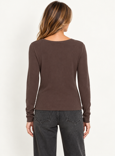 a woman facing backward in a ribbed brown long sleeve and black jeans on a white background.