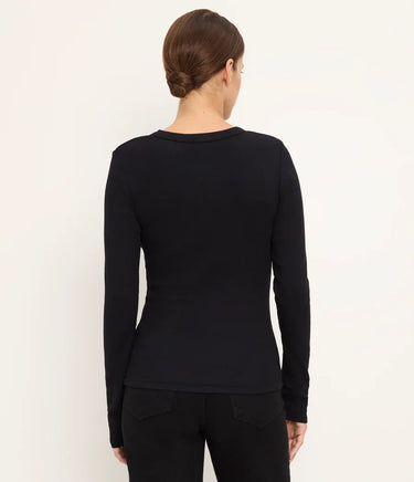 A woman viewed from the back wearing a fitted black long-sleeve top and black pants against a plain light background.