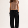Woman wearing a brown crop top and black wide-leg pants on a white background