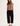 Woman wearing a brown crop top and black wide-leg pants on a white background