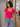 Woman wearing a bright pink shirt and blue jeans in a store setting