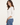 A woman wearing a ribbed 3/4 sleeve chalk top with blue jeans on a white background
