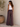 Woman wearing a white tank top and patterned wide-leg pants standing against a neutral wall.