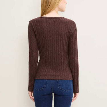 A woman shown from the back wearing a dark brown ribbed knit long-sleeve sweater and blue jeans against a plain light background.