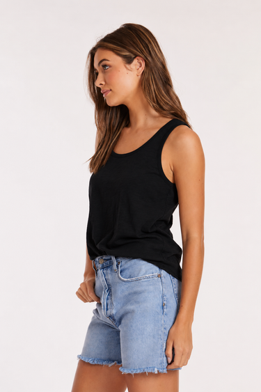 Woman wearing a black sleeveless top and blue denim shorts on a white background