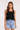 Woman wearing a black tank top and blue denim shorts on a white background