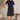 A woman wearing a black shirred waistband a-line midi skirt and a navy top on a neutral background