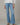 Person wearing light blue flared jeans on a neutral background