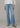 Person wearing light blue flared jeans on a neutral background