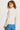Woman wearing a beige cargo jacket with blue pants on a white background