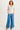 Woman wearing a beige jacket and blue pants on a white background