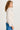 Woman wearing a cream jacket and blue pants on a white background