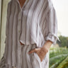 Person wearing a striped shirt and pants with a blurred natural background