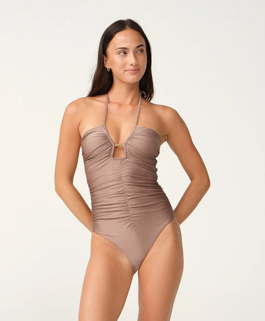 A woman wearing a shiny cutout halter cocoa swimsuit on a white background.