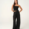 A woman wearing black pants with a side lace panel and a black tube top.