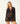 A model wearing a black bikini under a black lace long-sleeve tunic cover-up with scalloped pattern, lace-up V-neck and tassel ties.