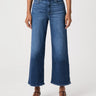 A model wearing a pair of high-waisted, wide-leg cropped blue denim jeans with a faded wash, paired with brown strappy sandals and a striped top, against a plain white studio background.