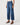 A model wearing a pair of high-waisted, wide-leg cropped blue denim jeans with brown wedge sandals, shown from the waist down on a light gray studio background.
