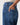Close-up of a person wearing blue denim jeans, showing the back pocket with a hand inserted, against a light gray background.