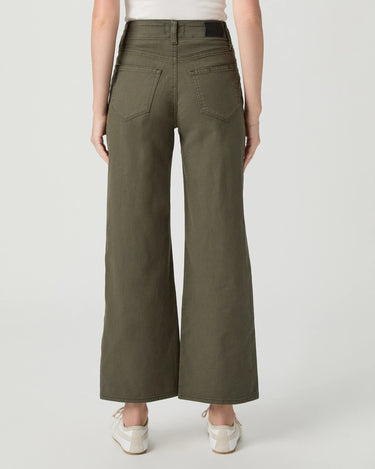 A person shown from the back wearing olive green wide-leg cropped pants, a white top, and white sneakers against a light gray studio background.