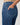Close-up of blue jeans with a hand in the pocket against a neutral background