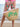 Person holding a straw bag with. Embriodered  green palm designs on a beach.