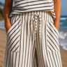 Person wearing a striped shirt and pants with a blurred beach background