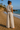 Woman in a striped outfit standing on a beach with ocean and cliffs in the background