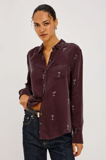 a woman wearing a burgundy blouse with Martin glasses printed on and dark blue denim on a white background.
