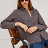 Woman wearing a striped shirt and sunglasses sitting on a chair with a white background