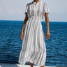 Woman in a striped dress standing by the ocean