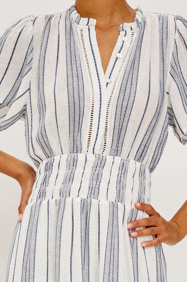 White dress with blue stripes worn by a person on a white background